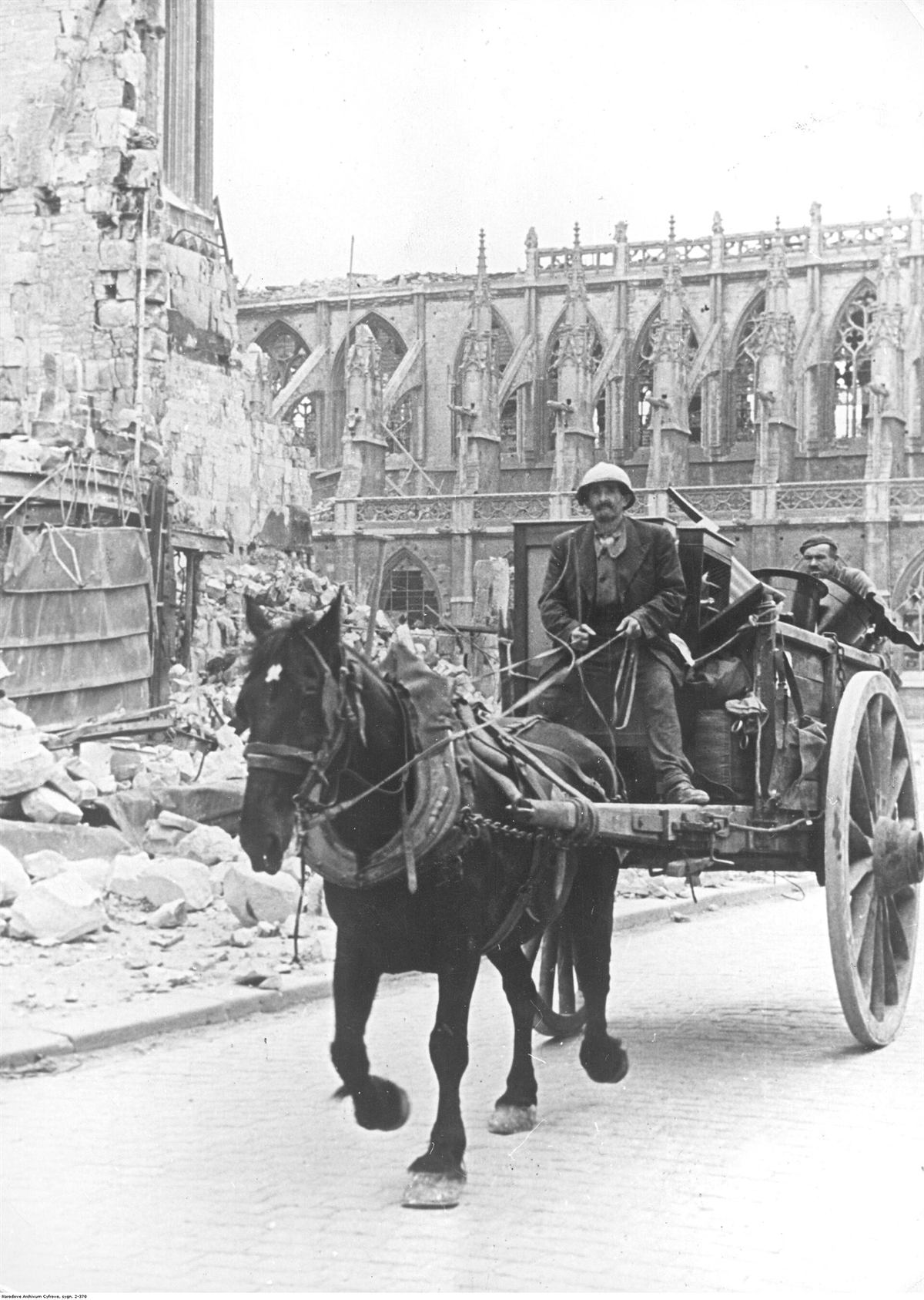 Mann med hest og kjerre foran den utbombede katedralen i Caen